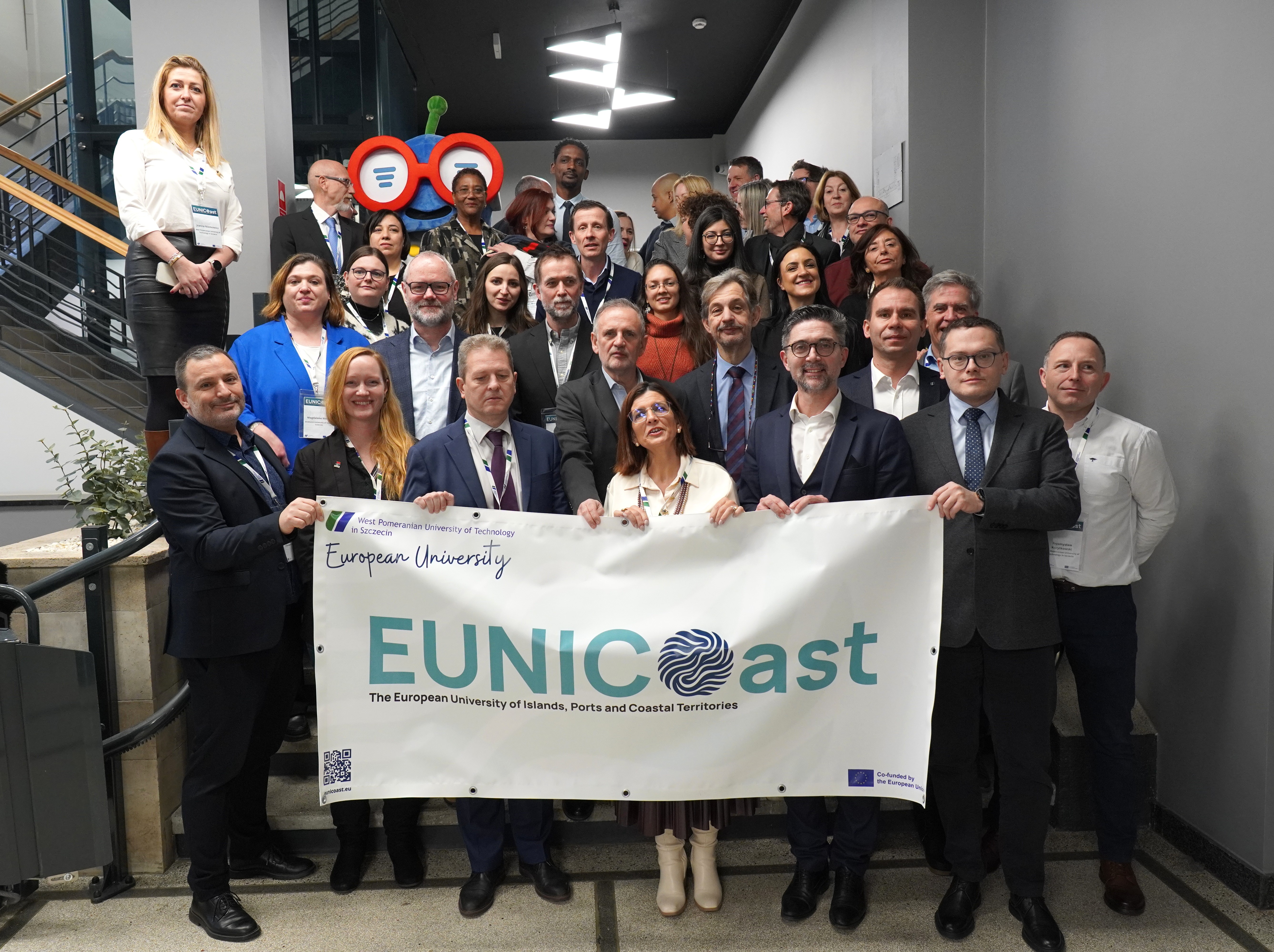 Group of EUNICoast representatives standing at the stairs with the alliance logo